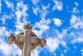 Christian stone cross against blue sunny cloudy sky