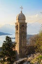 A Christian stone tower with a cross on its dome against a background of sea and mountains. Sunset time. The concept of Royalty Free Stock Photo