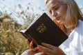 Christian teenage girl reading the Bible in the field. Faith, spirituality and religion concept Royalty Free Stock Photo