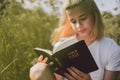 Christian teenage girl reading the Bible in the field. Faith, spirituality and religion concept Royalty Free Stock Photo