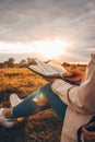 Christian woman holds bible in her hands. Reading the Holy Bible in a field during beautiful sunset. Concept for faith,