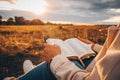 Christian woman holds bible in her hands. Reading the Holy Bible in a field during beautiful sunset. Concept for faith, Royalty Free Stock Photo