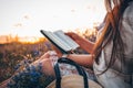 Christian woman holds bible in her hands. Reading the Holy Bible in a field during beautiful sunset. Concept for faith, Royalty Free Stock Photo