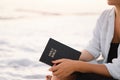 Christian woman holds bible in her hands. Reading the Holy Bible on the sea during beautiful sunset Royalty Free Stock Photo