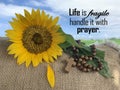 Christianity inspirational quote - Life is fragile, handle it with prayer. With wooden rosary and sunflower on brown and blue sky.