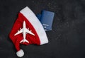Christmas airplane travel concept. Passports, toy white plane. Gold stars and Santa Cause hat on black background Royalty Free Stock Photo