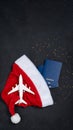 Christmas airplane travel concept. Passports, toy white plane. Gold stars and Santa Cause hat on blackbackground Royalty Free Stock Photo