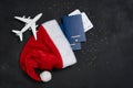 Christmas airplane travel concept. Passports, toy white plane. Gold stars and Santa Cause hat on black Royalty Free Stock Photo