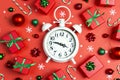 Christmas alarm clock with gift boxes and decorations on a red background. Christmas timer