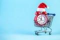 Christmas alarm clock in a supermarket trolley on a blue background