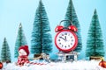 Christmas alarm clock on a wooden sled in the snow, with snowman toy