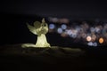 christmas angel on blur bokeh city lights at night on background. Little white guardian angel in snow Royalty Free Stock Photo