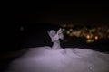 christmas angel on blur bokeh city lights at night on background. Little white guardian angel in snow Royalty Free Stock Photo