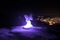 christmas angel on blur bokeh city lights at night on background. Little white guardian angel in snow Royalty Free Stock Photo