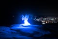 christmas angel on blur bokeh city lights at night on background. Little white guardian angel in snow Royalty Free Stock Photo