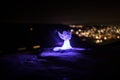 christmas angel on blur bokeh city lights at night on background. Little white guardian angel in snow Royalty Free Stock Photo