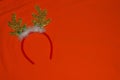 Christmas antlers of a deer with bells on orange background. Pair of toy reindeer horns. Merry Christmas and Happy New Year symbol