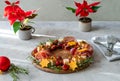 Christmas appetizers wreath on wooden board and grey background, star of Christmas plant or Poinsettia, napkin, forks