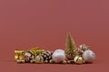 Christmas arrangement with golden miniature pine tree, bauble ornaments, bells, gift boxes and pine cones on brown background