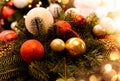 Christmas arrangement with pine twigs, red, white, gold balls, cones on the background of a christmas tree with beautiful bokeh Royalty Free Stock Photo