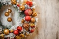 Christmas artificial wreath covered with white snow with golden and red decoration in the left corner Royalty Free Stock Photo