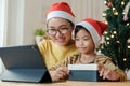 Christmas. Asian family with a mother and daughter giving gift box via video call together with tablet at home