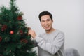 Christmas. Asian man standing new christmas tree at home celebrating New Year.