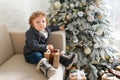 Christmas Baby , Child holding Gift Box sitting near christmas tree on the sofa at home Royalty Free Stock Photo