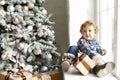 Christmas Baby , Child holding Gift Box sitting near christmas tree on the sofa at home Royalty Free Stock Photo