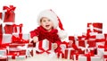 Christmas Baby with Gift Boxes. Happy Child in Santa Hat next to Stack of Xmas Presents with Red Ribbon Bow over White Background Royalty Free Stock Photo