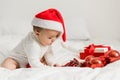 Christmas Baby in Santa Hat, Child holding christmas bauble near Present Gift Box over Holiday Lights background Royalty Free Stock Photo