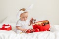 Christmas Baby in Santa Hat Child playing with baubles. Present Gift Box over Holiday Lights background and Merry Royalty Free Stock Photo