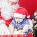 Christmas baby and Santa opening a present or gift box