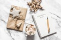 Christmas background - blank notepad with christmas plans, gift box, cup of hot chocolate on a light background, top view Royalty Free Stock Photo