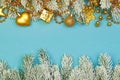Christmas background border. Colorful Gold Xmas composition with garland, gifts and green Xmas tree branch on blue background