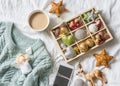 Christmas background. Box of vintage christmas decorations, coffee with milk, phone and blue knitted sweater on the bed, view from Royalty Free Stock Photo