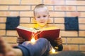 Christmas background. The boy is sitting near the fireplace with a book. Child with yellow lights. Waiting for the new year. Royalty Free Stock Photo