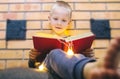 Christmas background. The boy is sitting near the fireplace with a book. Child with yellow lights. Waiting for the new year. Royalty Free Stock Photo