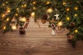 Christmas Background. Brown Wooden Table Top with Xmas Lights and Fir tree Branches. Christmas Decoration with Warm Lighting Royalty Free Stock Photo