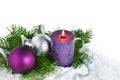 Christmas background with candle and decorations. Purple and silver Christmas balls over fir tree branches Royalty Free Stock Photo