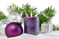 Christmas background with candle and decorations.Purple and silver Christmas balls over fir tree branches in the snow Royalty Free Stock Photo