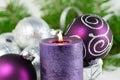 Christmas background with candle and decorations.Purple and silver Christmas balls over fir tree branches in the snow Royalty Free Stock Photo