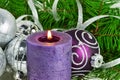 Christmas background with candle and decorations. Purple and silver Christmas balls over fir tree branches in the snow Royalty Free Stock Photo
