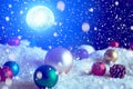 Christmas background with Christmas balls on snow over fir-tree, night sky and moon. Shallow depth of field. The elements of this Royalty Free Stock Photo