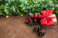 Christmas background with decorative composition of green tinsel, dried oranges, red berres, pine cone, gift with red bow and