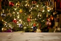Christmas background: empty wooden table on the foreground and an out of focus Christmas tree on the background