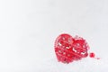 Christmas background - festive red bauble - heart with deers print in shiny white snow closeup, copy space. Royalty Free Stock Photo