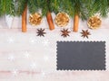 Christmas background with fir branches, cone, present, snowflakes, toy, cinnamon, anise and black nameplate on brown wooden Royalty Free Stock Photo