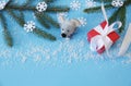 Christmas background with fir branches and a rat and snowflakes and a red gift box with a white ribbon on a blue background. Royalty Free Stock Photo