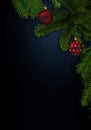 Christmas background with fir branches and red balls. Christmas tree border with holiday decor on dark blue backdrop Royalty Free Stock Photo